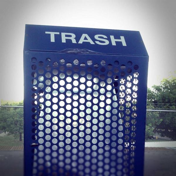 A blue trashcan with holes in the frame so you can see the clear trashbag inside along with the contents