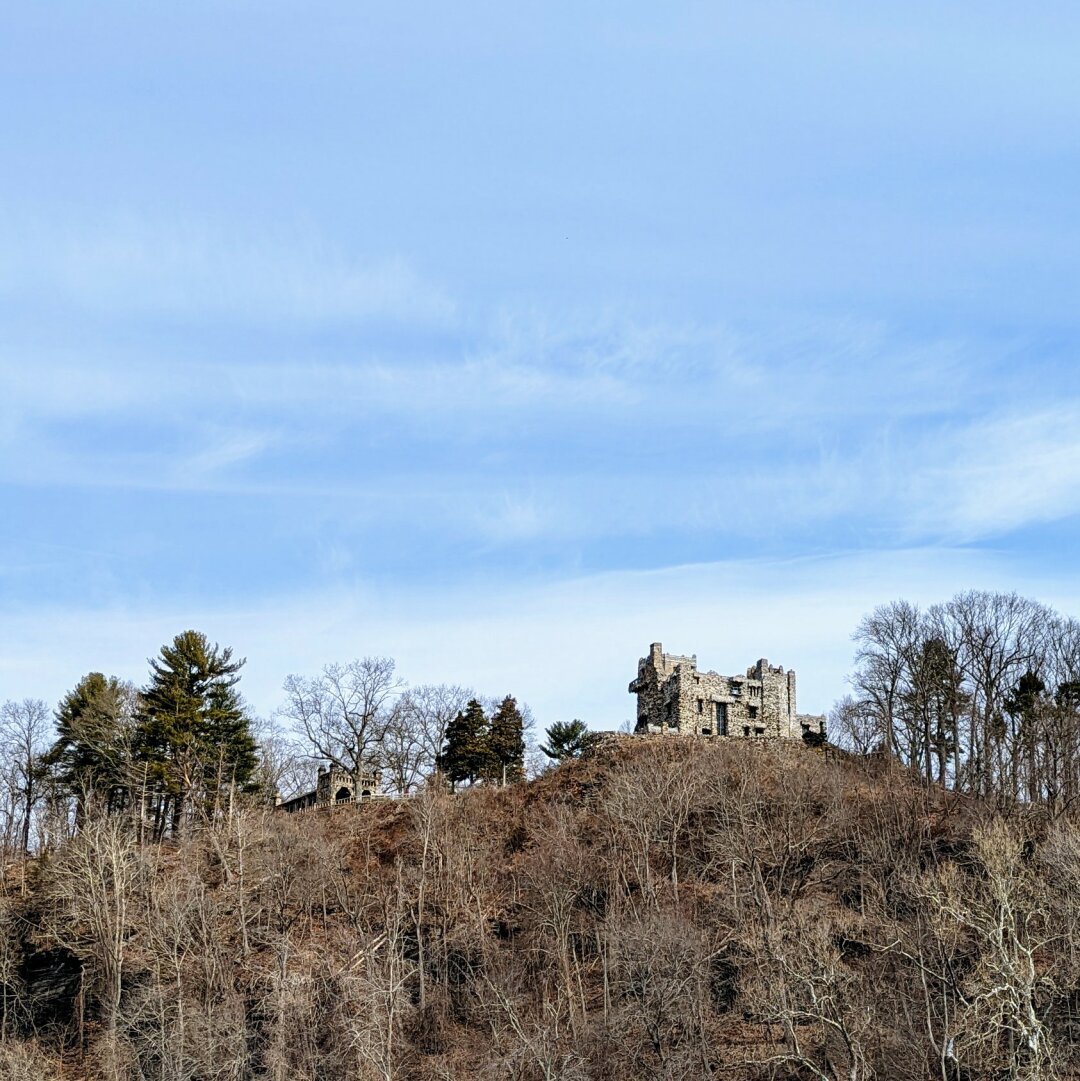 A stone castle that looks in ruins on top of a hill on an island