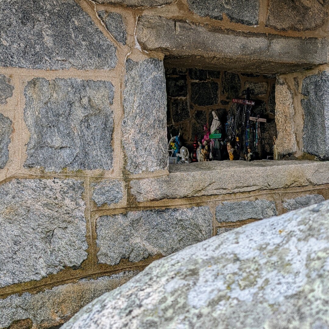 Looking into a stone chapel, statues sitting on the mantel