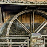 A wooden waterwheel on the side of a very old wooden building