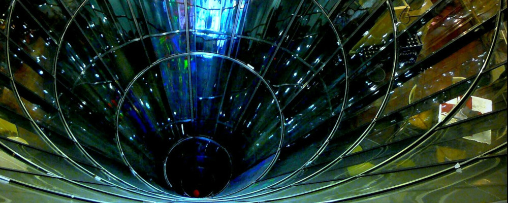 Looking down a cylindrical pit made of glass with offices on the other side.
