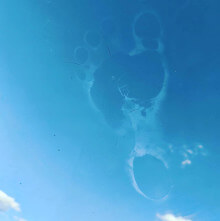a footprint against a glass window with clouds in the background